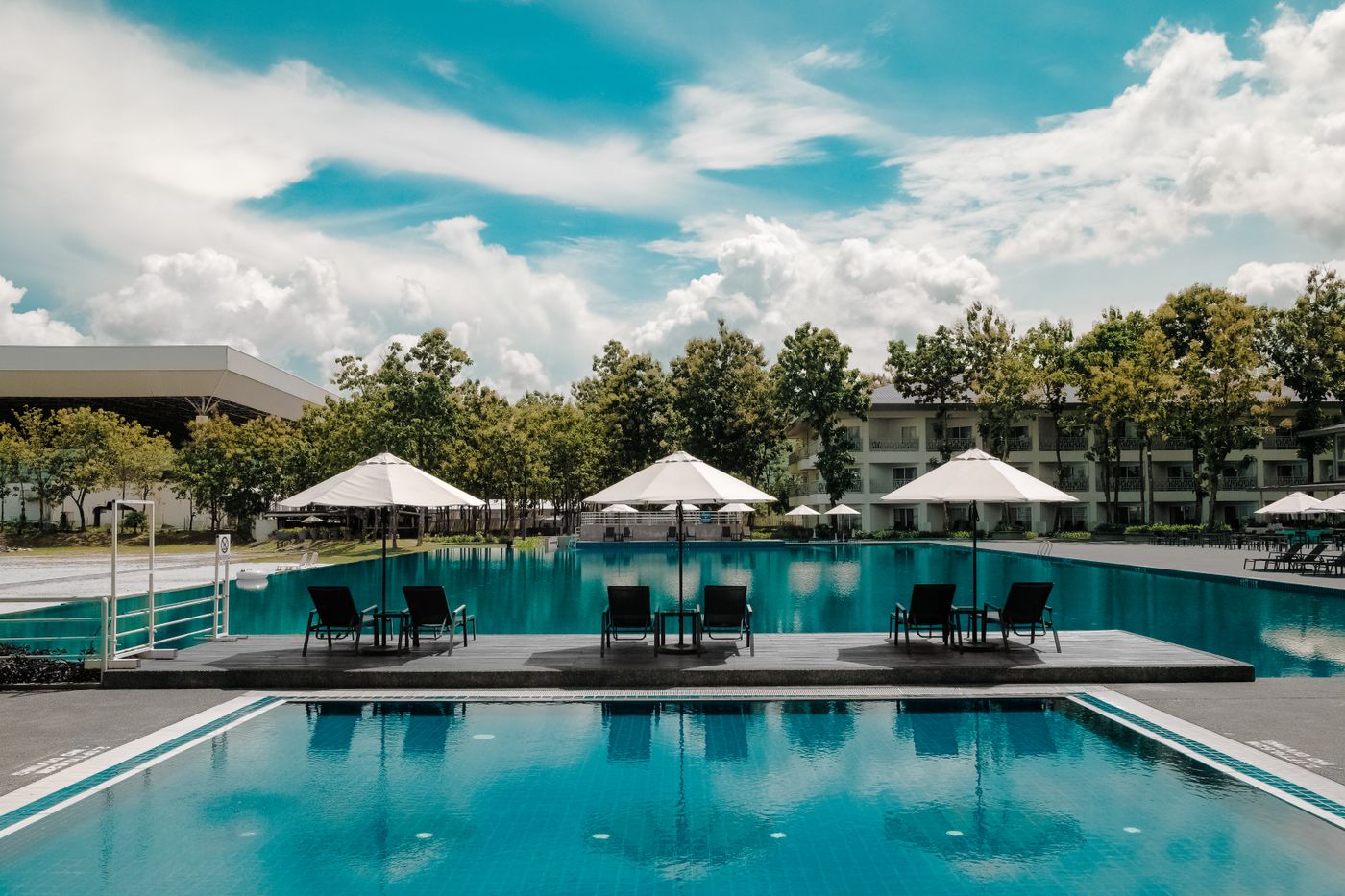 Large outdoor pool bordered by sun umbrellas and seating